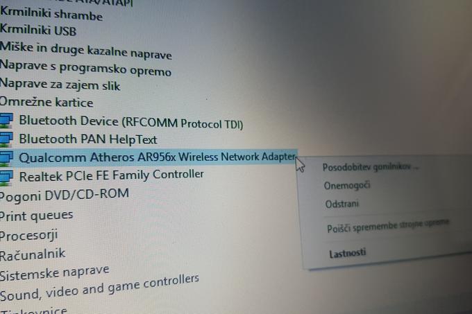 Na osebnem računalniku moramo nadgraditi gonilnik antene Wi-Fi. Na računalniku z Windowsi to storimo tako, da odpremo Upravitelja naprav (Device Manager), poiščemo in razširimo meni Omrežne kartice, z desno tipko kliknemo na komponento, kjer piše <znamka><model>Wireless Network Adapter (na fotografiji označeno z modro) in izberemo možnost Posodobitev gonilnika. Windows bo nato poiskal morebiten novi gonilnik. Če ga ne bo našel, ga poskusimo na spletu poiskati sami (v spletni iskalnik vnesemo ime modela naše antene Wi-Fi in pripišemo "driver", kar je angleška beseda za gonilnik).  | Foto: Matic Tomšič