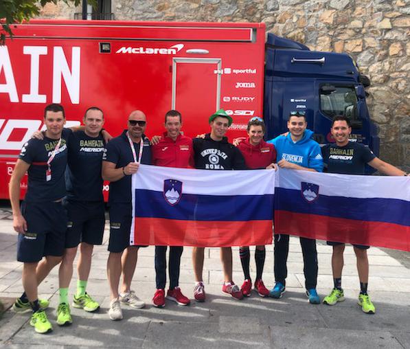 Domen Novak in Luka Pibernik (v rdečem puloverju) s slovenskim osebjem pri Bahrain Meridi in navijačema, ki v Španiji ponosno vihtita slovensko zastavo. | Foto: Siol.net/ A. P. K.