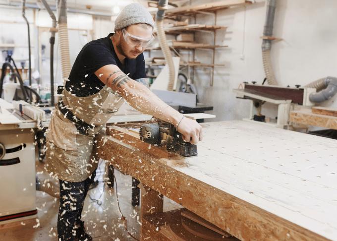 Carpenter working with electric planer on wooden plank in workshop. Craftsman makes own successful small business._1200 | Foto: Petrol