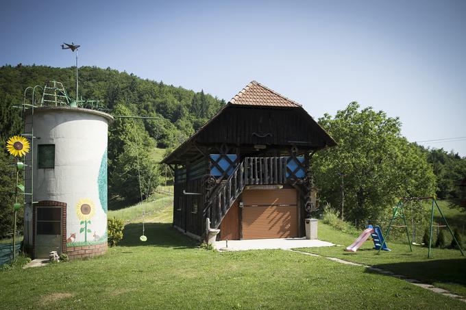 Pri starem silosu, ki je danes porisan in ga uporabljajo kot shrambo, stoji sončnica iz nerjavečega jekla. Je delo njenega moža, postavil ji jo je namesto mlaja za 50 let. Na strehi silosa je staro orodje, na drugih pa so letala z vrtečimi se propelerji, ki jih je Andrej prav tako naredil iz nerjavečega jekla. | Foto: Ana Kovač