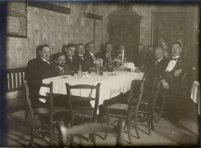 Družba penatov z gostilničarjem Tomažem Biziljem (stoji v sredini), fotografirana v Gostilni Pri kolovratu po odkritju spominske plošče Andreju Smoletu leta 1926. | Foto: Zbirka upodobitev znanih Slovencev, NUK