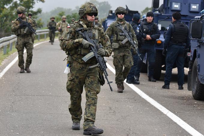 Kosovo je še vedno jabolko sporo na Balkanu, saj se mu Srbi ne nameravajo odpovedati. Tudi kosovska stran pogosto skuša napenjati mišice. Nedavno so tako izbruhnile napetosti na kosovsko-srbski meji, ko je Priština uvedla nova pravila glede uporabe registrskih oznak. Kosovski Srbi so v znak protesta z vozili blokirali dostop do dveh mejnih prehodov, Priština pa je na mejo poslala posebne policijske enote. Beograd je takoj dvignil bojno pripravljenost srbske vojske na meji s Kosovom, območje pa so preletavala tudi srbska letala. Po pritisku mednarodne javnosti so se strasti umirile. Na mejo so tako prišle enote Kforja. Na fotografiji: poljski pripadniki Kforja, v ozadju kosovski policisti v modrih uniformah.  | Foto: Reuters