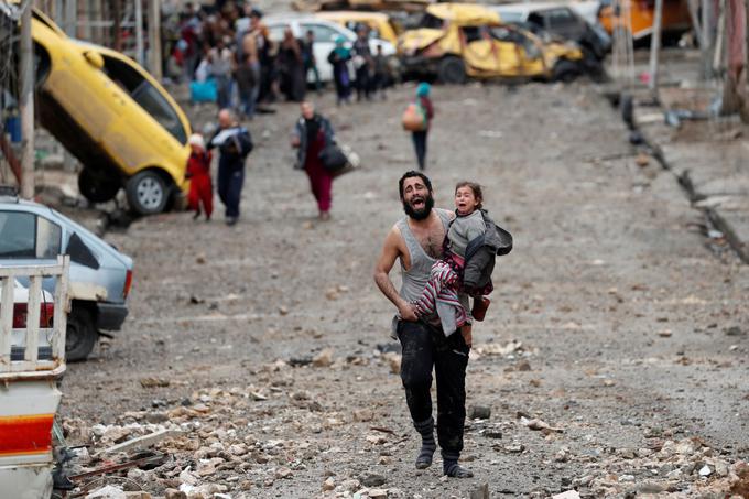 Moški in njegova hči jočeta med približevanjem iraškim vojakom, ki so izpod nadzora ekstremistov Islamske države osvobodili del mesta Mosul, marec 2017. | Foto: Reuters