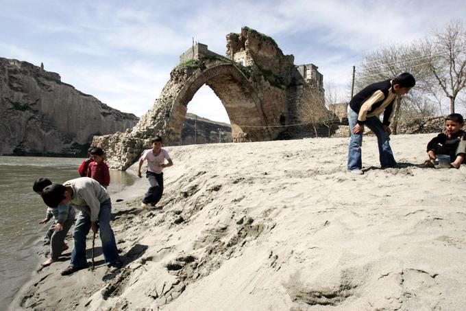 Otroška igra ob ostankih tisočletnega kamnitega mostu čez Tigris, ki bo ob dvigu rečne gladine najverjetneje postal domovanje rib. | Foto: Reuters