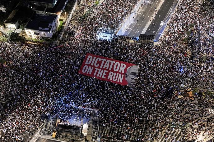 Protesti v Izraelu | Na velikem transparentu z rdečim ozadjem, ki so ga nosili demonstranti v Tel Avivu, je ob sliki predsednika vlade Benjamina Netanjahuja pisalo: "Diktator na begu." | Foto Reuters