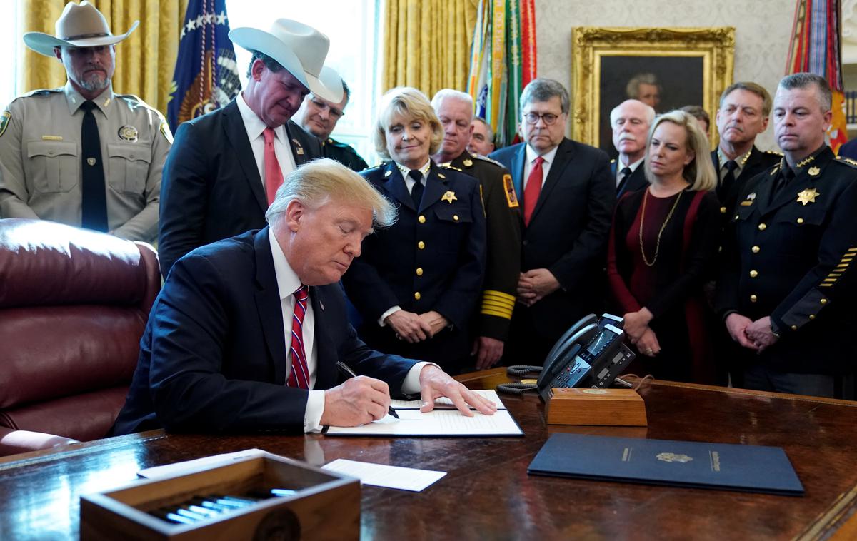 Donald Trump | Ameriški predsednik Donald Trump se je v Ovalni pisarni Bele hiše ob podpisu veta obkrožil z možmi v uniformah in starši otrok, ki so jih umorili nezakoniti priseljenci. | Foto Reuters