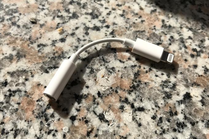 Adapter za iPhone 7 in iPhone 7 Plus, ki omogoča uporabo slušalk s 3,5-milimetrskim priključkom kljub temu, da ga telefona nimata. Nadležno je, ker ga je treba vedno nositi s seboj, ker je tako majhen, pa ga lahko neroden uporabnik hitro izgubi. | Foto: Matic Tomšič