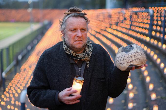 Volker-Johannes Trieb s svečo in žogo, napolnjeno s peskom, ki predstavljata trpeče delavce migrante v Katarju. | Foto: Reuters