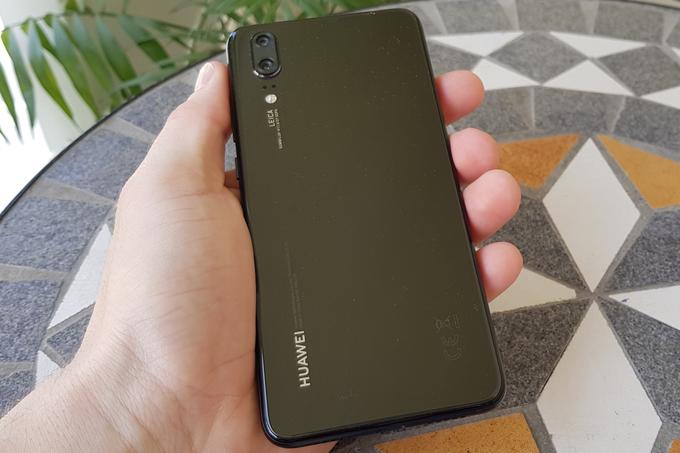 Naš preizkusni huawei je bil povsem črn, na voljo pa je tudi v bolj drznih barvah, med drugim v zelo zanimivi mavrični, ki se imenuje Twilight in pri kateri se barve pravzaprav prelivajo po pokrovu baterije. Na fotografiji se sicer lepo vidi, da je stekleno črno ohišje huaweija P20 pravi magnet za prašne delce.  | Foto: Matic Tomšič