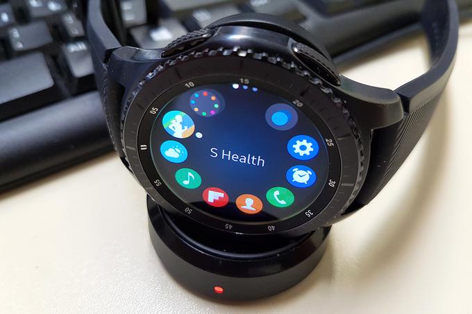 Ko ura Samsung Gear S3 Frontier postane lačna elektrike, poteka polnjenje njenega 380-miliamperskega akumulatorja (baterije) prek brezvrvičnega polnilca (na sliki spodaj z rdečo lučko med polnjenjem), ki z rahlo magnetno silo uro varno pritrdi nase. | Foto: Srdjan Cvjetović