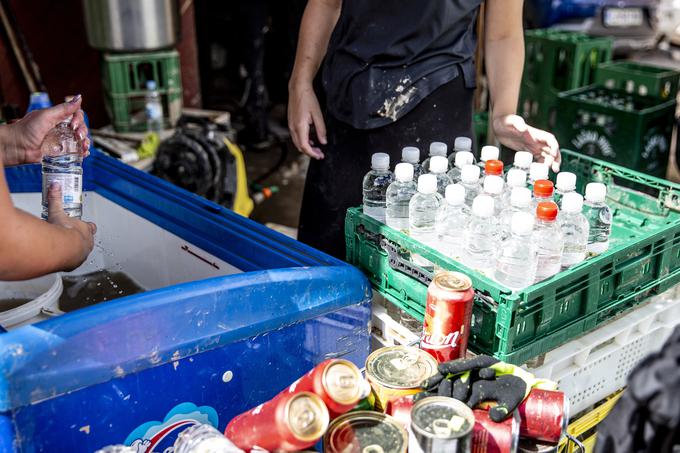 Ljudje se trudijo rešiti, kar se da. Izpirajo blatne plastenke, ki jih namerava lastnica trgovine prodati po znižani ceni. Veliko večino stvari iz trgovine pa je voda uničila in bodo romale na odpad.  | Foto: Ana Kovač